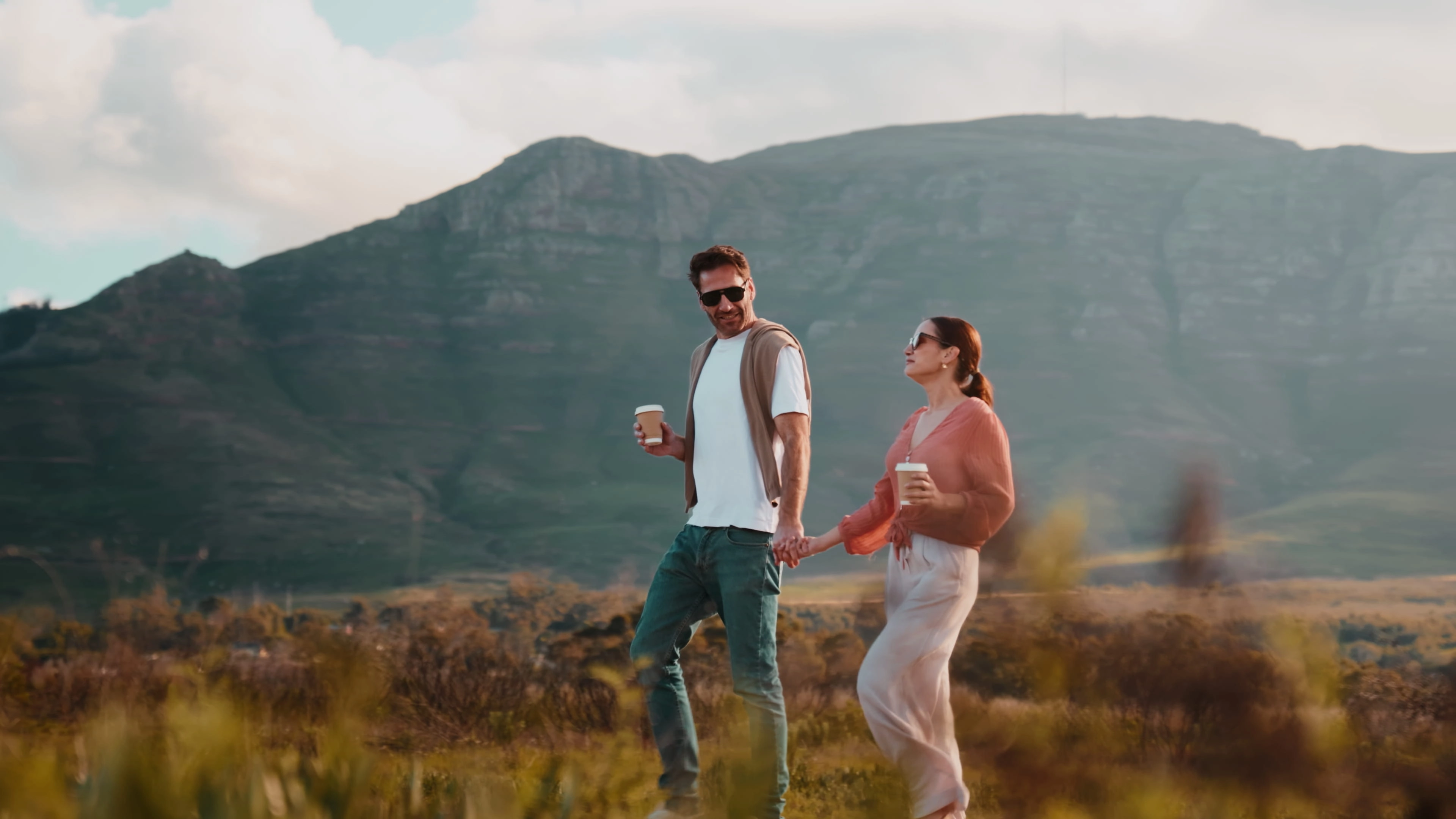 A couple walking with coffee on the mountain slopes above Tokai