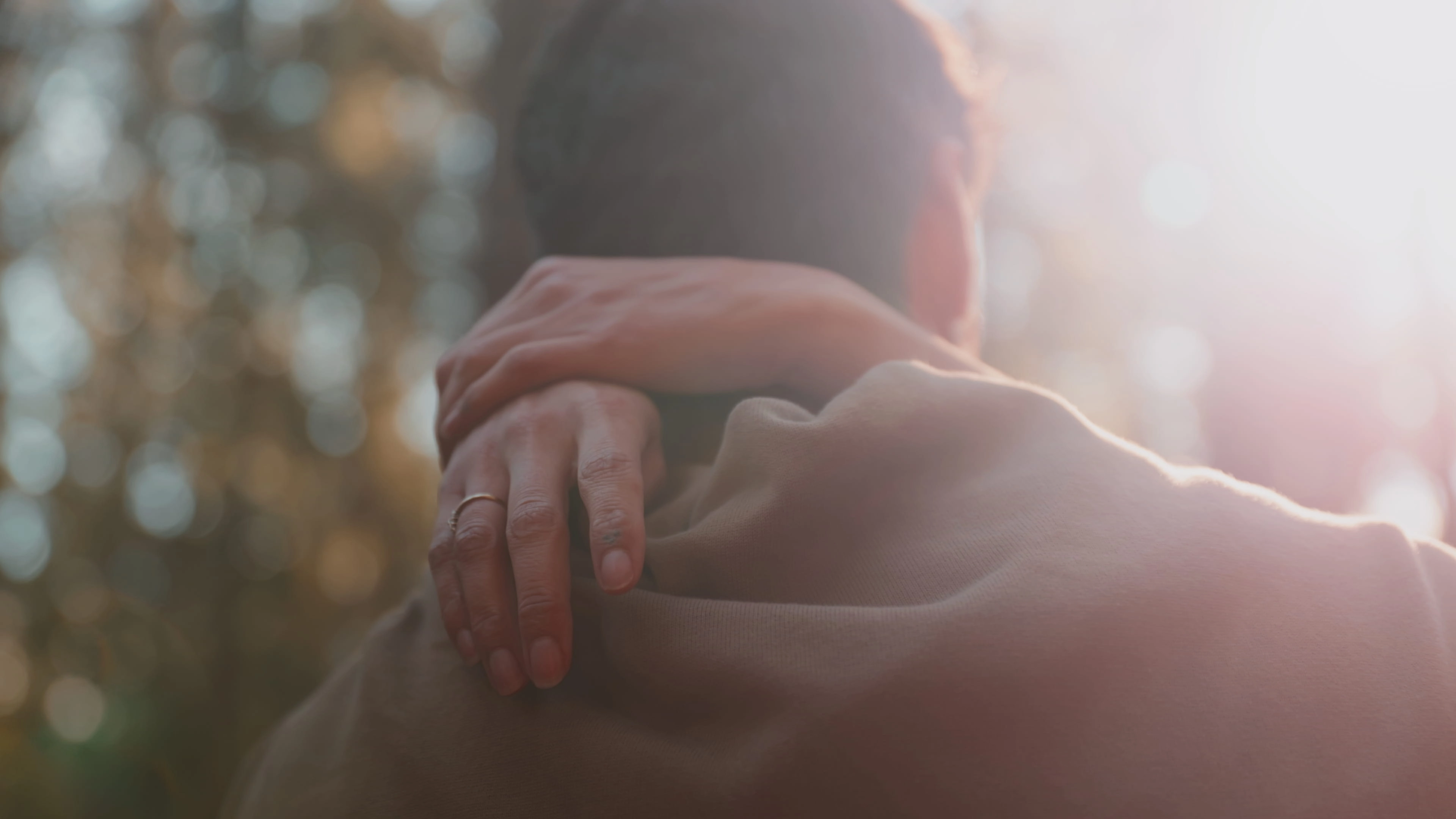 Two people embracing in the late afternoon light, a hand resting on a shoulder